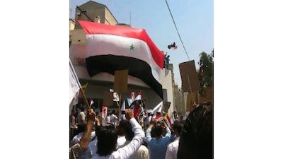 Pro-Assad demonstrators hang a huge Syrian flag at the entrance of the US embassy compound in Damascus as they protest against the US ambassador, Robert Ford, after his visit to the Syrian city of Hama.