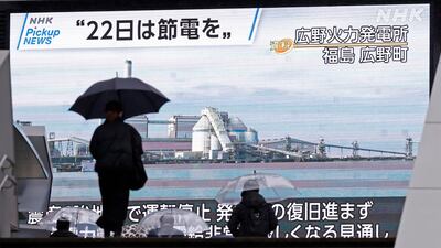 People in Tokyo walk past a screen showing a news programme calling for power saving in March last year. Japan’s government had alerted people to potential power cuts after several coal-fired plants temporarily stopped generating electricity following an earthquake. AP