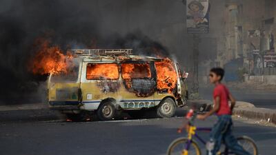 A Pakistani youth wheels his bicycle past a burning vehicle on a street in Karachi on Tuesday following the arrest of Altaf Hussain, head of Pakistan's Muttahida Qaumi Movement party, in London. Asif Hassan / AFP