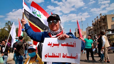 An anti-government protester holds a placard in Arabic that reads, "the people want to bring down the regime," during a rally in Baghdad, Iraq. AP Photo