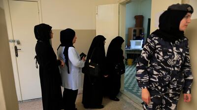 A Lebanese policewoman, right, stands next to women who are queuing to cast their vote at a ballot station during the Lebanon's parliamentary elections in a southern suburb of Beirut, Lebanon. Hassan Ammar / AP Photo