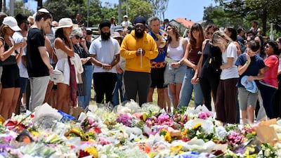 Mourners gather by floral tributes to the victims, one of whom was a 10-year-old girl. AFP