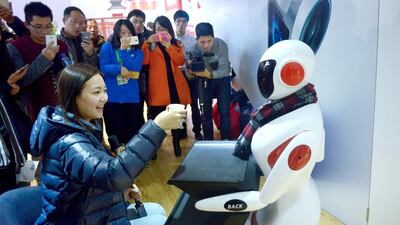 A robot delivers a cup to a visitor during a demonstration at the World Robot Conference. Wang Zhao / AFP