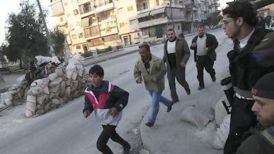 Residents run to take cover as Free Syrian Army fighters take position behind sandbags during clashes with forces loyal to Syria's president Bashar AlAssad in Aleppo.