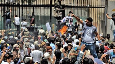 A Yemeni protester burns a US flag as others storm the US embassy in Sanaa.