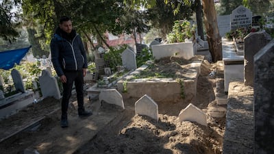 Baris Yapar stands by his grandparents' graves. He believes they could have been saved had rescue and recovery teams arrived faster
