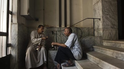 Salama, left, eats breakfast with Hagag Mohammed, a fellow bawaab, in the foyer to the apartment building where he works in Cairo. The pair are part of tens of thousands of migrant workers across Cairo who function as doormen, car parkers, errand runners, night watchmen, gardeners and just about anything.
