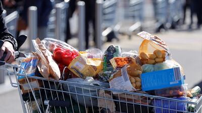 A customer walks with a shopping trolley full of products as people queue to enter a supermarket in Hoenheim near Strasbourg, France. Christian Hartmann / Reuters