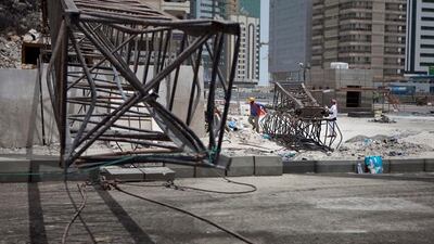 Construction workers work away to clean up remains of a crane that collapsed earlier that morning on Tuesday, July 12, 2011, during the morning rush hour in downtown Abu Dhabi. No one was hurt and only road blocks and the crane itself suffered damages. (Silvia Razgova/The National)