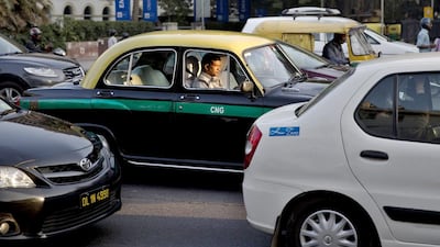 An Indian taxi driver drives an Ambassador cab with the distinctive yellow and black livery through the traffic in New Delhi. The Indian capital on Monday banned taxi-booking service Uber after a woman accused one of its drivers of raping her. Bernat Armangue / AP Photo
