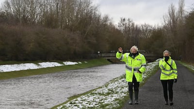 British Prime Minister Boris Johnson walks with Environment Agency workers during a visit to a storm basin near the River Mersey in Didsbury. AFP