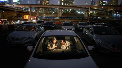 A couple look at a mobile phone as they sit in a car at a screening at a drive-through cinema in Seoul, South Korea. AFP