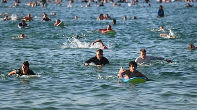 Surfers and swimmers head out into the ocean in a tribute to those killed in the December 14 shooting at Bondi Beach, in Sydney, Australia. AP