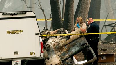 A sheriff's deputy recovers the remains of a Camp Fire victim from an overturned car in Paradise, California. AP Photo