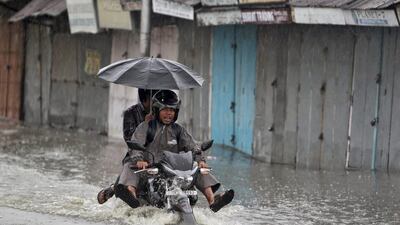 Men ride on a motorcycle through a flooded street during a rain shower in Agartala. Jayanta Dey / Reuters