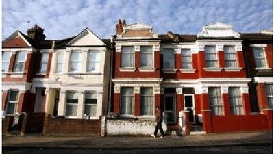 A man walks past a row of London terrace houses.