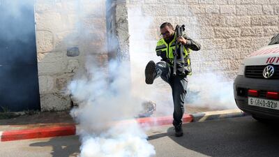 A Palestinian cameraman kicks away a tear canister fired by Israeli forces during a protest to show solidarity with Muath Amarneh in the West Bank city of Bethlehem. EPA