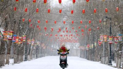 A woman rides a motorcycle past a snow-covered street decorated with lanterns, ahead of the Chinese Lunar New Year, in Zhangye, Gansu province, China. Reuters