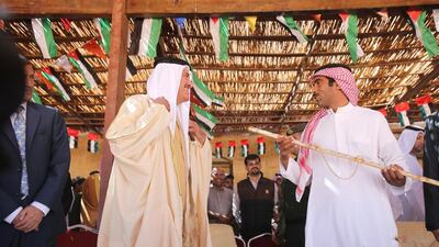 Emirati Sheikh Sultan Bin Hamdan prizes a sword to the first winner of the female camels race on camels race using robotic jockeys in the desert of Wadi Rum valley, south of Jordan.