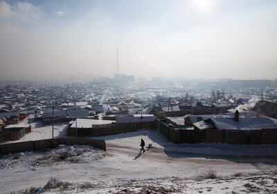 A man walking down an icy road, as smoke rises from chimneys of houses mixing with smog on a polluted day in Ulaanbaatar, the capital of Mongolia. Byambasuren Bymaba-Ochir / AFP