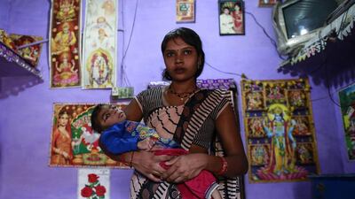 Five-year-old Saagar, who suffers from mental and physical disabilities is held by his mother Komal, as she poses for a picture at their house in a slum in Bhopal.
