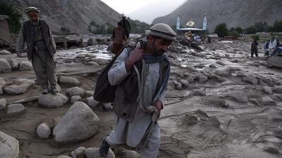 An Afghan villager carries belongings over his shoulder following a landslide at Peshghor village, in Khenj District in Afghanistan's northern Panjshir province. AFP/Wakil KOHSAR