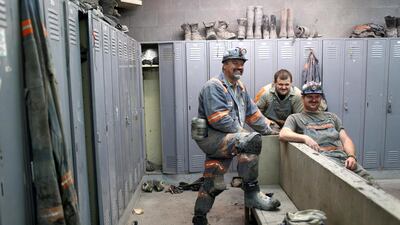 Coal miners Rodney Blankenship, left, Roger Vanatter, centre, and an unidentified colleague prepare for the start of their afternoon shift in the locker room of a coal mine near Gilbert, West Virginia. Robert Galbraith / Reuters