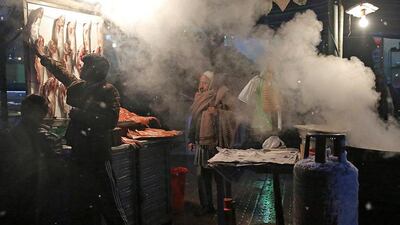 An Afghan man, center, waits as he buys fish at a street stall street during a snow storm in Kabul, Afghanistan. Massoud Hossaini / AP Photo