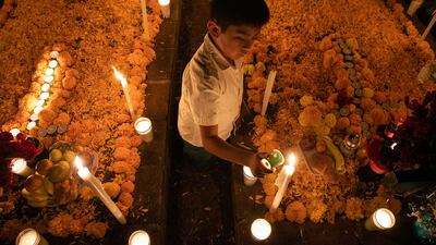 A boy lights candles as he attends a Night of the Dead celebration. People adorn the tombs of the dead and remain in the pantheon throughout the night waiting for their relatives. Tradition says that on the night of November 1 and early morning of November 2, the souls of the dead return to the world of the living. AFP