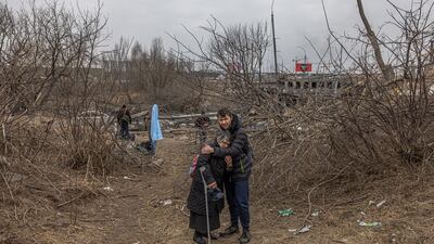 A man hugs an elderly woman after crossing a damaged bridge as they flee from the frontline town of Irpin, near the Ukrainian capital of Kyiv. EPA