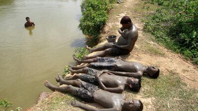 People relax after applying mud on their bodies to cool off on a hot summer day on the banks of the Kanchon Mala lake on the outskirts of Agartala, India. Jayanta Dey / Reuters