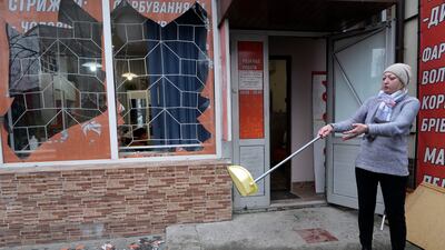 A Kiev resident sweeps up debris after Russian shelling. AP