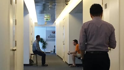 Investors and staff sit outside the closed office of Exential in Dubai Media City. Pawan Singh / The National