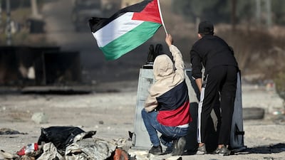 Palestinian boys wave their national flag as demonstrators clash with Israeli soldiers during a protest in Ramallah in the occupied West Bank. AFP