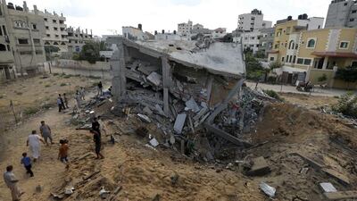 Palestinians gather around the remains of a house destroyed in an Israeli air strike in Gaza City yesterday. Photo: Reuter / Mohammed Salem