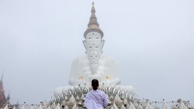 A devotee prays in front of big Buddha statues in the early morning mist, at Wat Phra That Pha Sorn Kaew temple, in Khao Kho, Phetchabun province, Thailand, September 21, 2024. REUTERS / Athit Perawongmetha