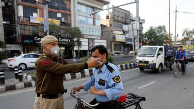 A policeman adjusts the mask of a security guard in New Delhi, India. Reuters