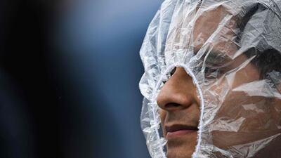 A spectator tries to stay dry while watching the 2024 Wimbledon Championships in London. AFP