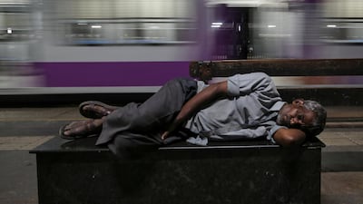 A man sleeps on a bench next to a passing train at a railway station in Mumbai, India. Reuters