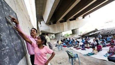 Rajesh Sharma teaches Savita Kumari, 12, words by rote at the makeshift school he founded under a metro bridge in Shakarpur, New Delhi.
