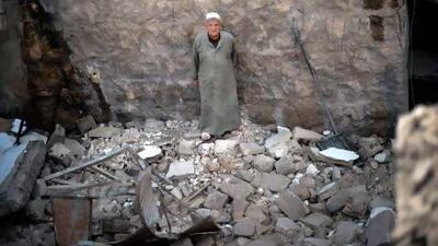 A man stands shocked in the remains of a house following an airstrike by the Syrian airforce in Aleppo.