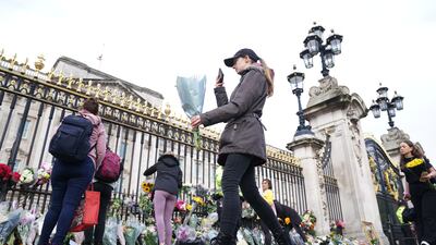 A woman lays flowers at Buckingham Palace in London following the death of Queen Elizabeth II on Thursday. Photo: PA