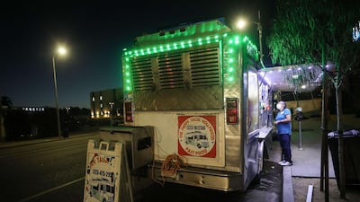 A customer orders from a taco truck in Los Angeles, California. California Governor Gavin Newsom ordered indoor dining restaurants to close again in Los Angeles County and 18 other counties for at least three weeks amid a surge in new coronavirus cases. Restaurants and food trucks may remain open for takeout and drive-through orders. AFP