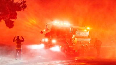 Firefighters spray down wildfire flames in California. AFP