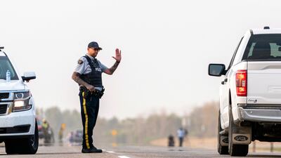 A police officer issues instructions to a driver on a road outside Rosthern, Saskatchewan. AP