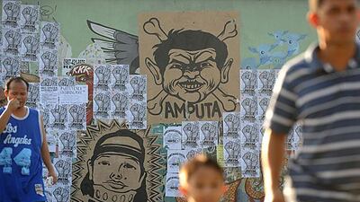 People walk past a wall with a caricature of former Philippine president Gloria Arroyo and Maguindanao massacre suspect Andal Ampatuan at an overpass in Quezon City, east of Manila. Noel Celis / AFP Photo