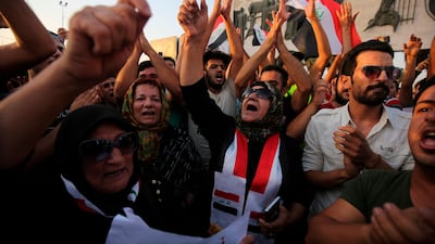 Iraqis wave national flags and hold up signs during a demonstration against unemployment in the capital Baghdad's Tahrir Square. AFP