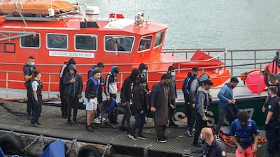 Migrants are escorted as they disembark a rescue boat in Calais, northern France after their inflatable vessel started taking on water. AFP
