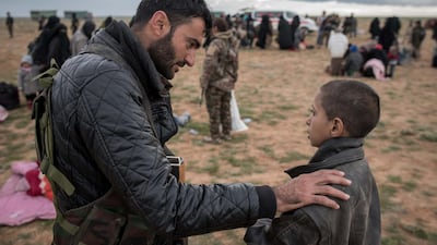 A 12-year-old orphan called Mohamed speaks with a fighter from the Syrian Democratic Forces after leaving Baghouz, the last ISIS-held territory in Syria. Campbell MacDiarmid for The National