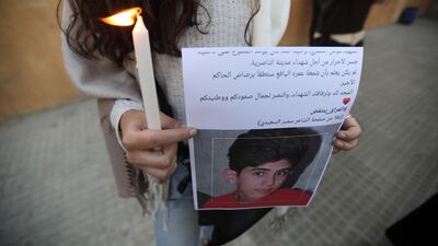 A Lebanese demonstrator holds a picture showing a young Iraqi killed during protests, as she takes part in a candlelight vigil staged outside Iraq's embassy to denounce the excessive use of force against demonstrators there, in the capital Beirut. AFP